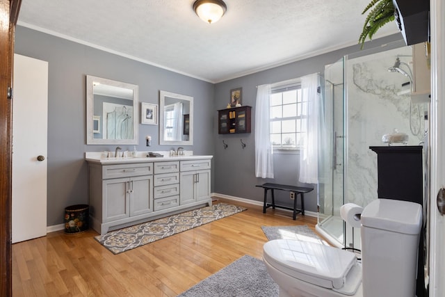 full bath with double vanity, wood finished floors, a stall shower, and a sink