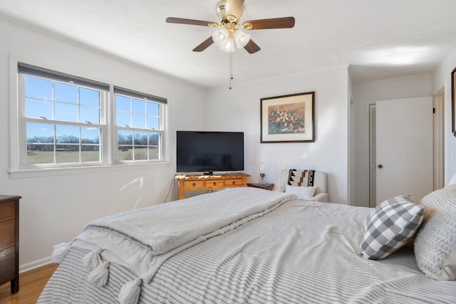 bedroom featuring a ceiling fan, baseboards, and wood finished floors