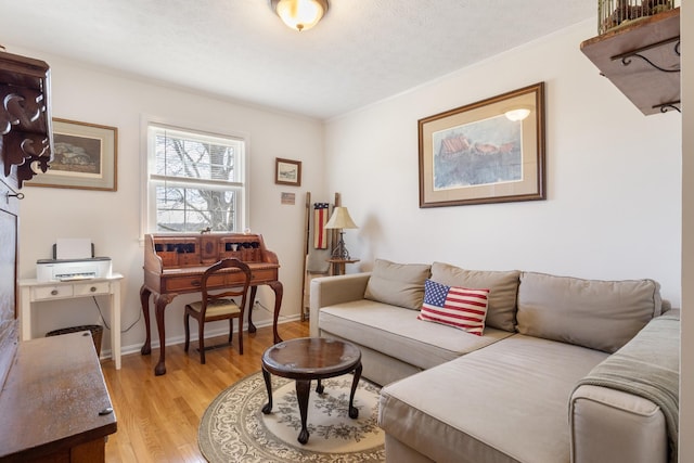 living room featuring light wood finished floors, a textured ceiling, baseboards, and crown molding