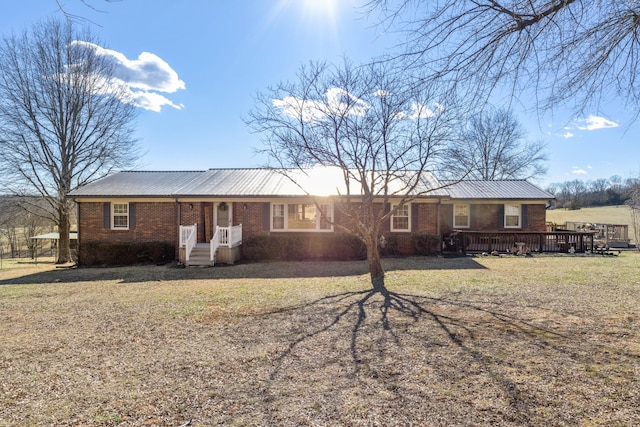 ranch-style house with metal roof, brick siding, and a front lawn