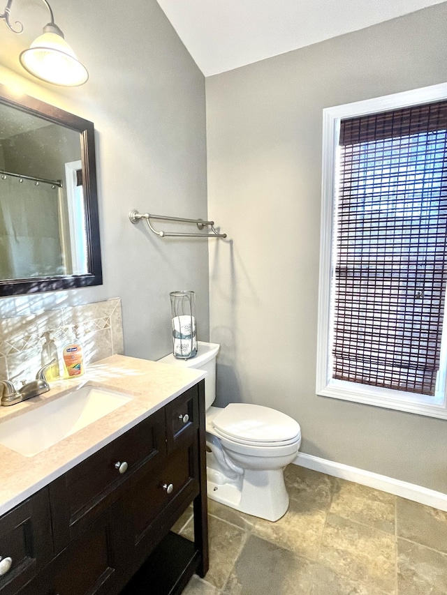 full bathroom with toilet, a healthy amount of sunlight, baseboards, and vanity