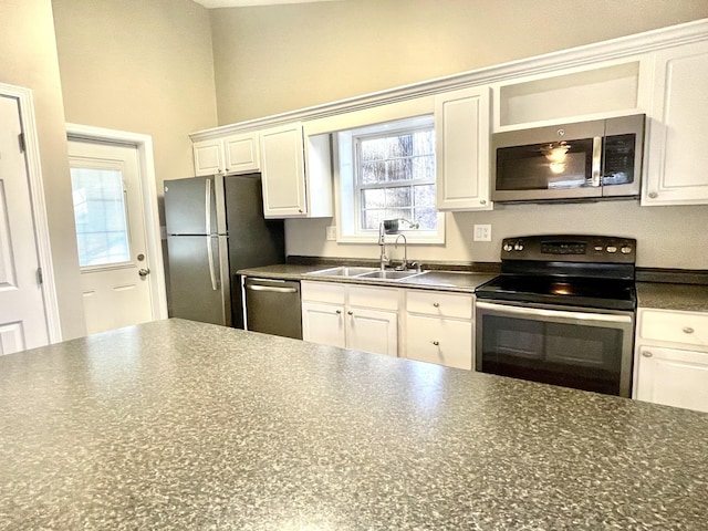 kitchen featuring open shelves, dark countertops, appliances with stainless steel finishes, white cabinets, and a sink