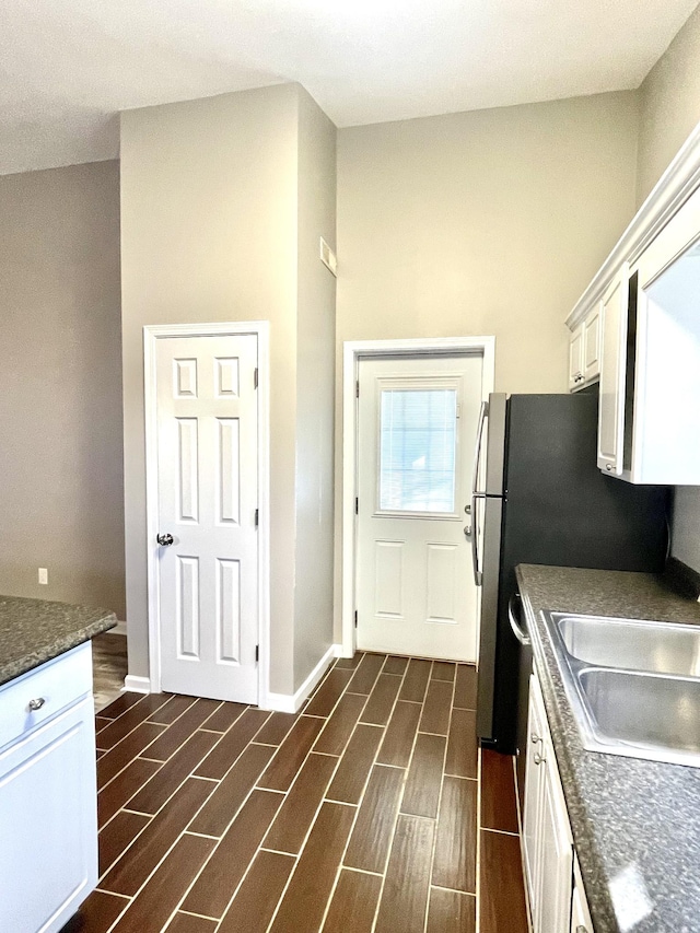 kitchen with baseboards, white cabinets, a sink, and wood finish floors