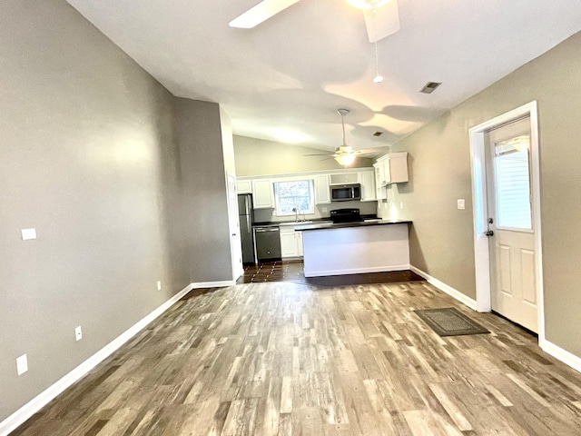 kitchen featuring dark wood-style floors, stainless steel appliances, a ceiling fan, white cabinetry, and a sink