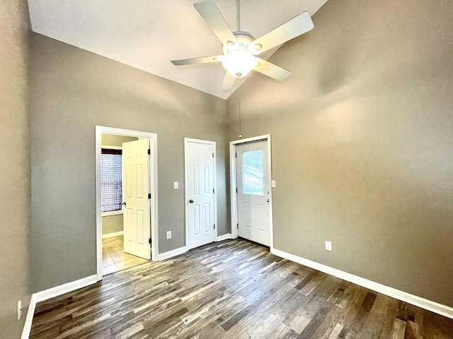 unfurnished bedroom featuring ceiling fan, ensuite bath, baseboards, and wood finished floors