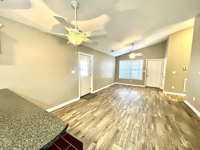 foyer entrance with a ceiling fan, lofted ceiling, baseboards, and wood finished floors