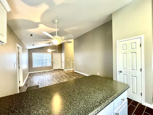 kitchen featuring white cabinets, dark wood-style floors, visible vents, and vaulted ceiling