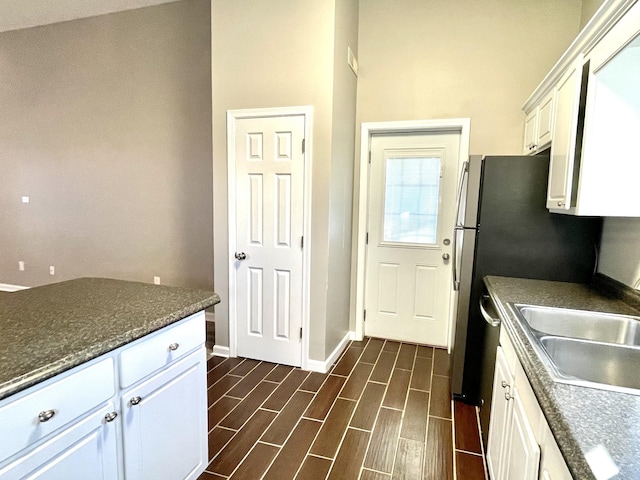 kitchen with baseboards, a sink, white cabinetry, and wood tiled floor