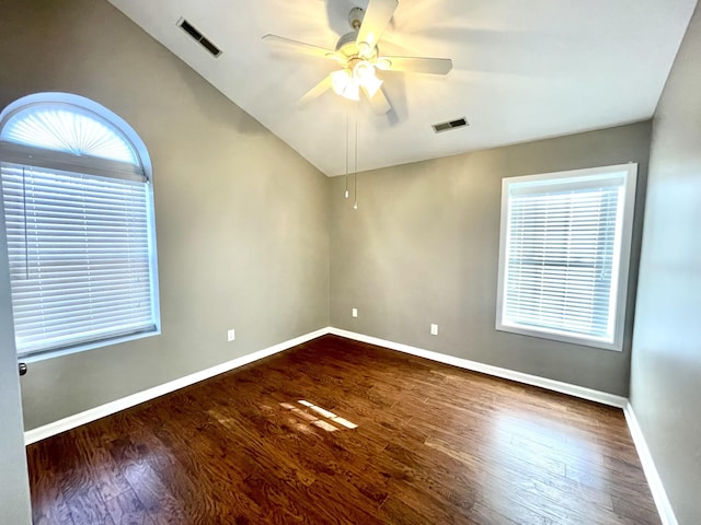 spare room with ceiling fan, wood finished floors, visible vents, baseboards, and vaulted ceiling