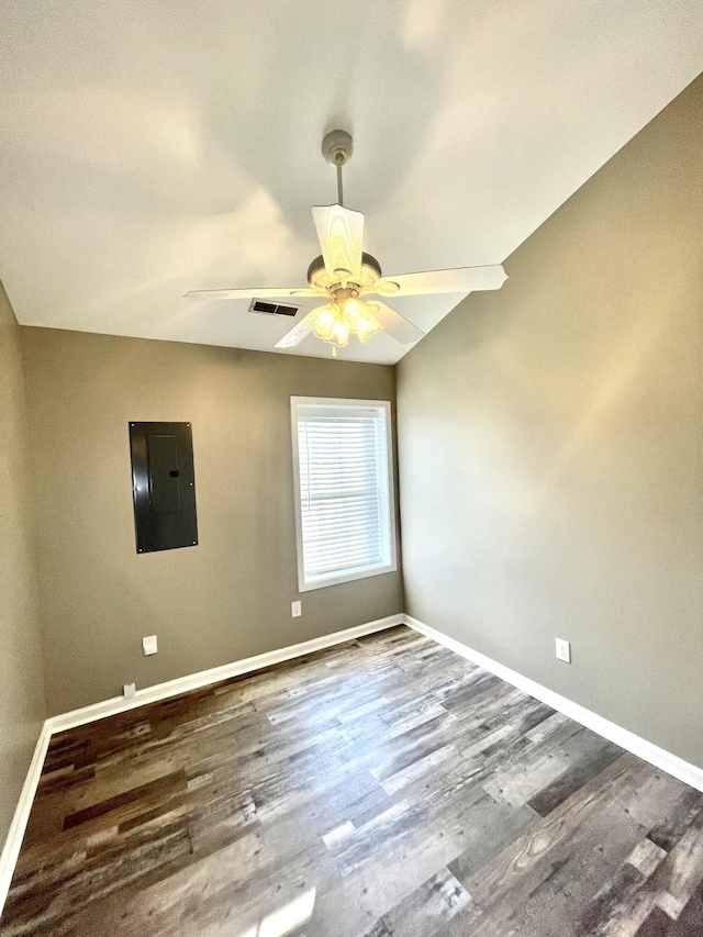 spare room with visible vents, a ceiling fan, wood finished floors, electric panel, and baseboards