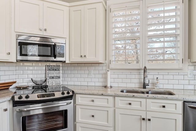 kitchen with light stone counters, tasteful backsplash, appliances with stainless steel finishes, white cabinetry, and a sink