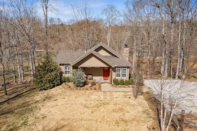 view of front of house featuring roof with shingles, a front lawn, and a chimney