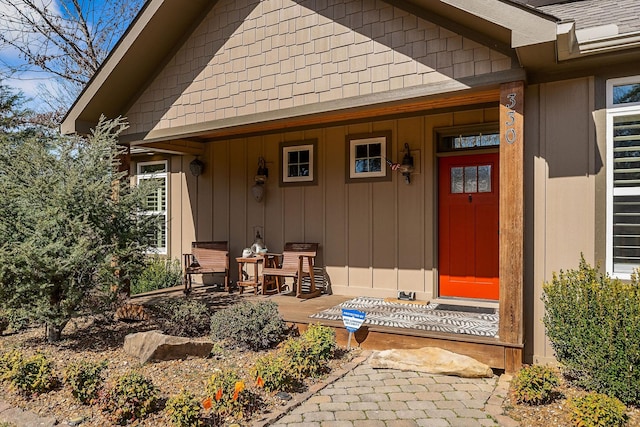 entrance to property with covered porch and roof with shingles