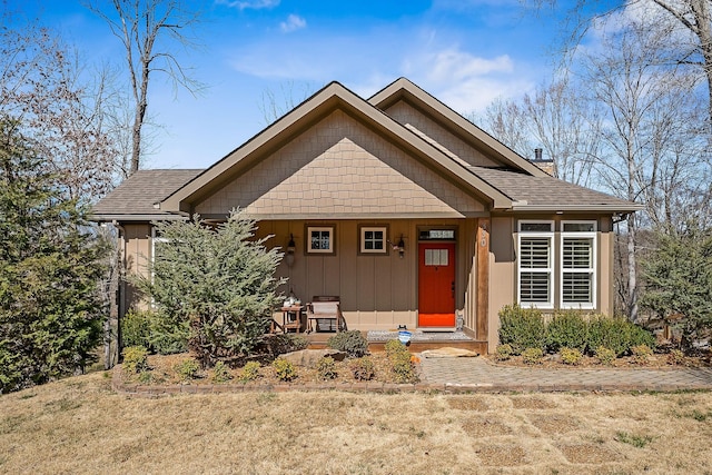 view of front of property featuring covered porch, a shingled roof, a chimney, and board and batten siding