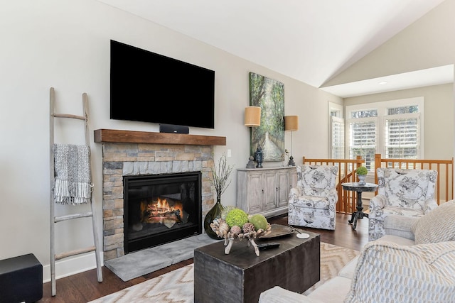 living room featuring lofted ceiling, a stone fireplace, and wood finished floors