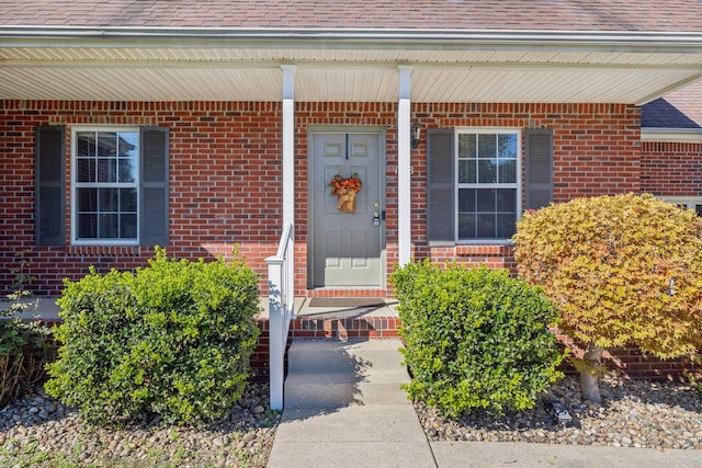 entrance to property featuring brick siding and roof with shingles