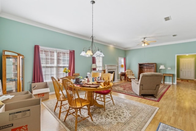 dining area with baseboards, visible vents, ornamental molding, wood finished floors, and a fireplace