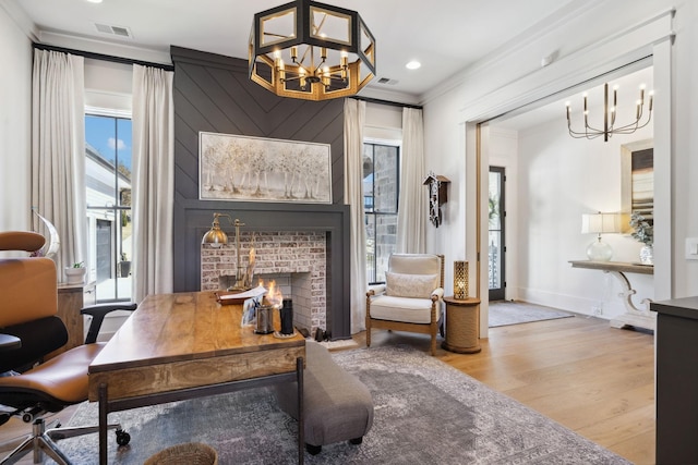 office area featuring an inviting chandelier, a fireplace, visible vents, and crown molding