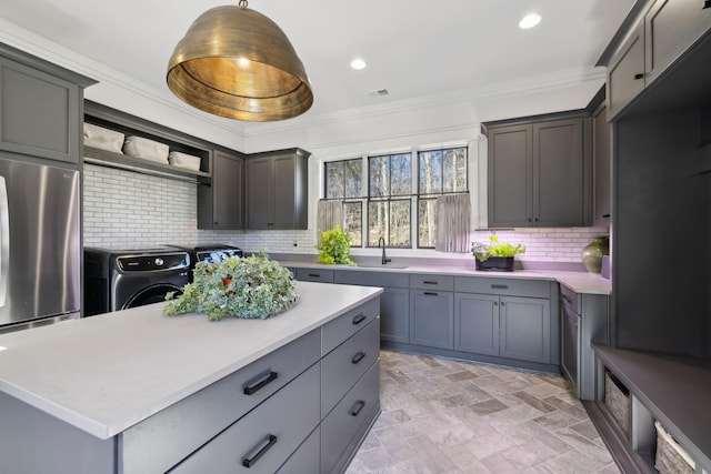 kitchen featuring a sink, light countertops, tasteful backsplash, and stainless steel fridge