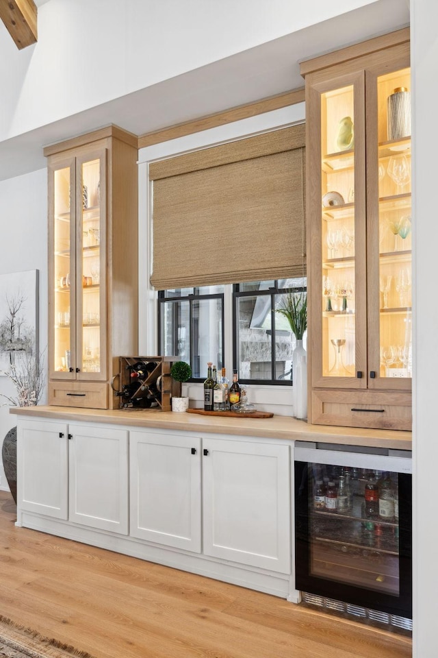 bar featuring light wood-style floors, wine cooler, and a bar