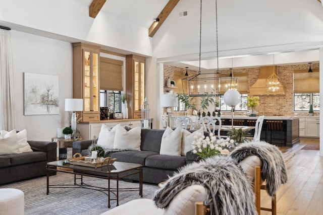 living room featuring high vaulted ceiling, visible vents, light wood-type flooring, a wealth of natural light, and beamed ceiling