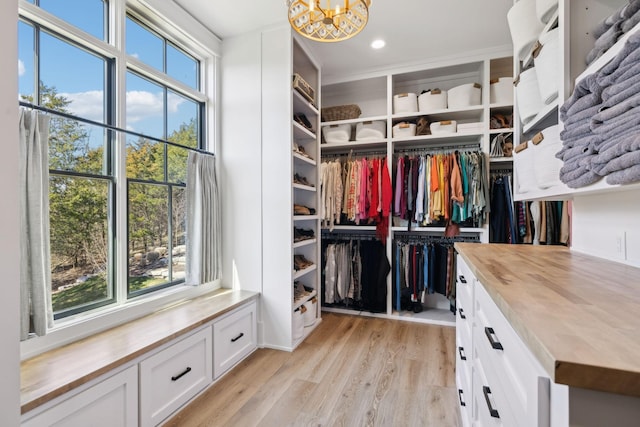 spacious closet featuring light wood-style floors and a notable chandelier