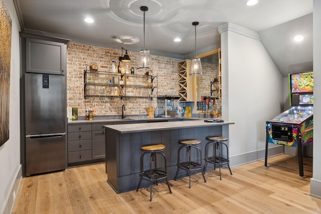 bar with light wood finished floors, brick wall, high quality fridge, and wet bar