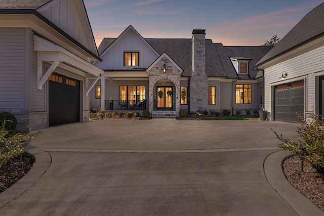 view of front facade with concrete driveway, stone siding, a chimney, an attached garage, and board and batten siding