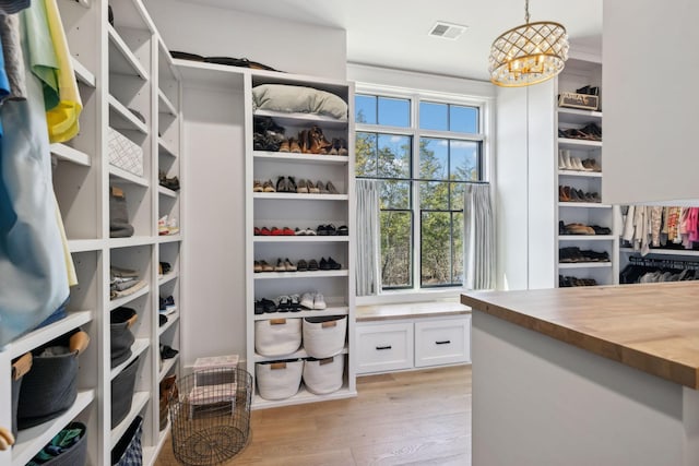 walk in closet featuring light wood-style floors, a chandelier, and visible vents