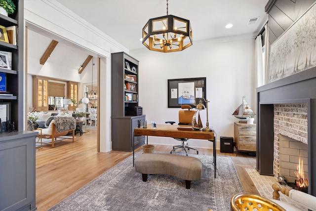 office space featuring an inviting chandelier, a fireplace, visible vents, and light wood finished floors