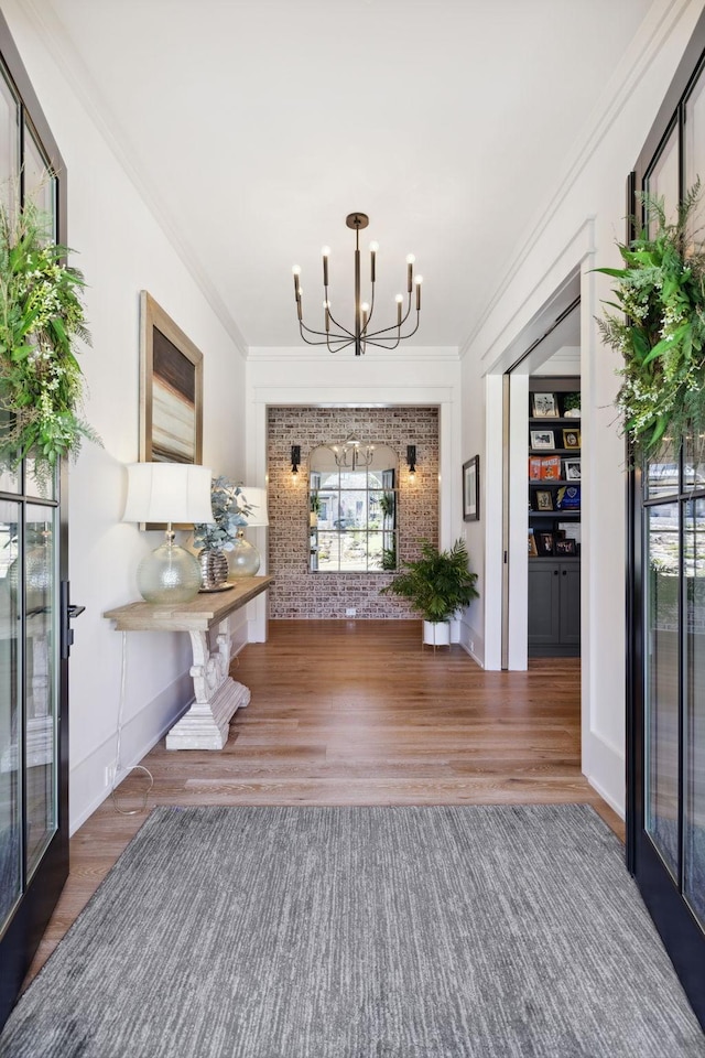 interior space with crown molding, wood finished floors, and an inviting chandelier