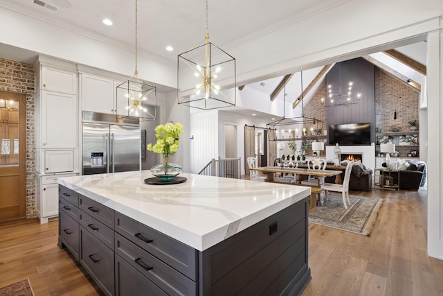 kitchen with white cabinets, a large fireplace, light wood-style flooring, and stainless steel built in refrigerator