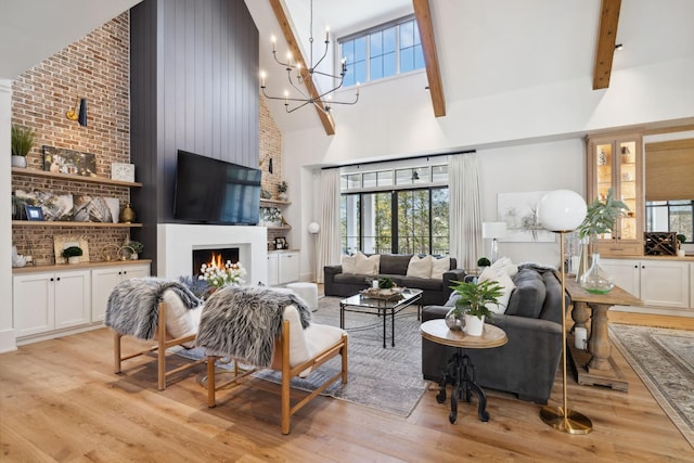 living area with a lit fireplace, light wood finished floors, and a high ceiling