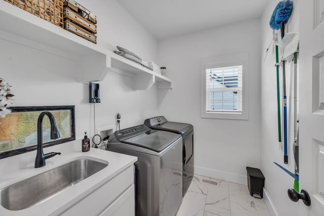 washroom featuring a sink, baseboards, marble finish floor, cabinet space, and washer and clothes dryer