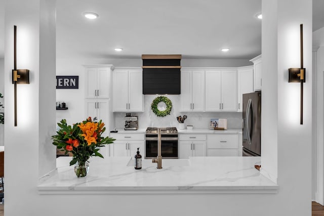 kitchen featuring light stone countertops, appliances with stainless steel finishes, white cabinets, and backsplash