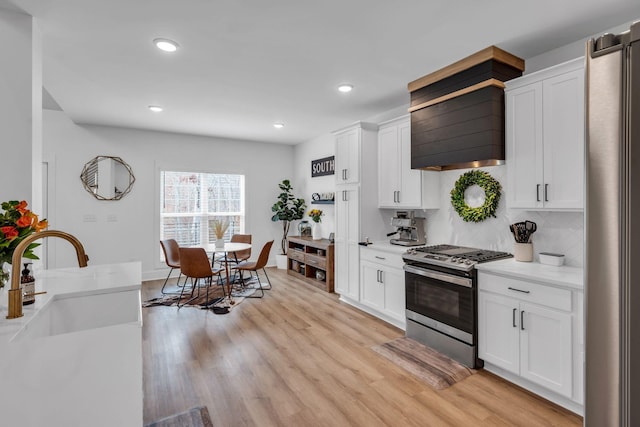 kitchen with light countertops, appliances with stainless steel finishes, light wood-style flooring, and white cabinetry