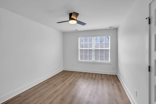 unfurnished room with ceiling fan, wood finished floors, visible vents, and baseboards