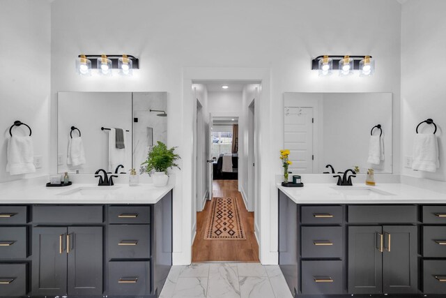 ensuite bathroom with marble finish floor, two vanities, and a sink