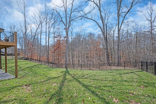 view of yard featuring fence, a view of trees, and a wooden deck