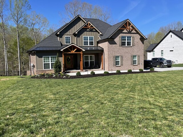 craftsman house featuring board and batten siding, brick siding, fence, and a front lawn