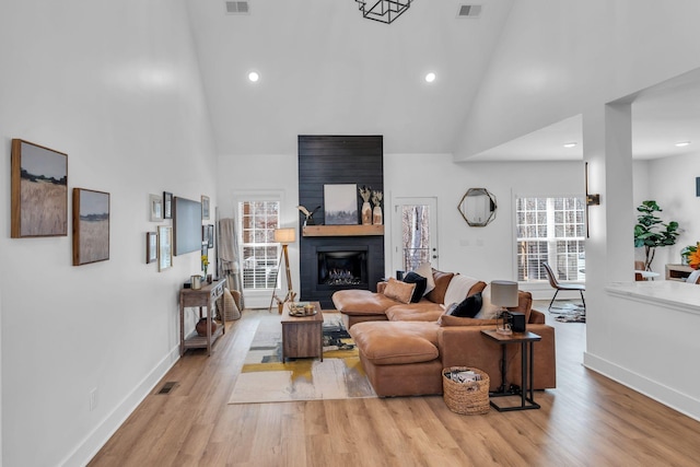 living room with high vaulted ceiling, a wealth of natural light, and wood finished floors