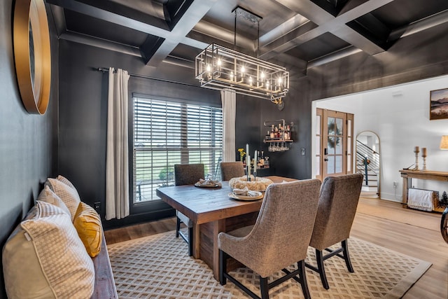 dining room with coffered ceiling, wood finished floors, baseboards, beamed ceiling, and an inviting chandelier