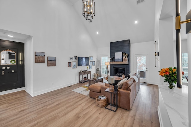 living area with light wood-style floors, baseboards, a fireplace, and high vaulted ceiling