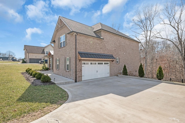 view of side of property with a standing seam roof, brick siding, a yard, and driveway