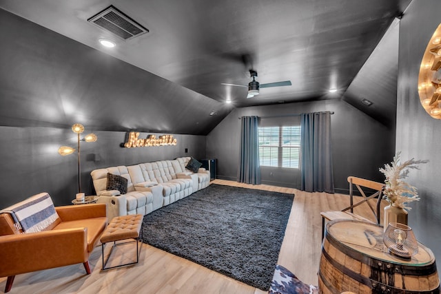 cinema room with lofted ceiling, visible vents, ceiling fan, and wood finished floors