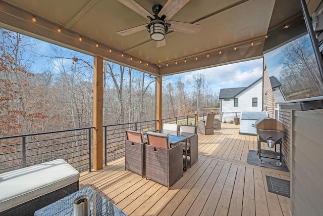 deck with outdoor dining space, grilling area, and a ceiling fan