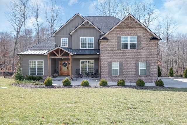 view of front of home featuring board and batten siding, a front yard, a standing seam roof, and brick siding