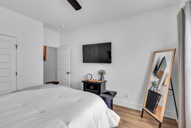 bedroom with ceiling fan, light wood-style flooring, and baseboards