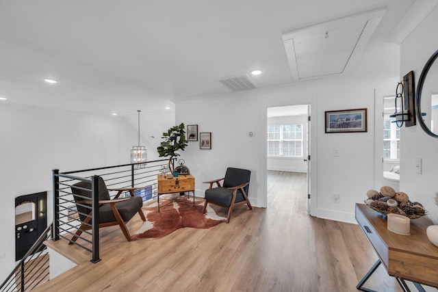 living area with visible vents, attic access, light wood-style floors, an upstairs landing, and baseboards