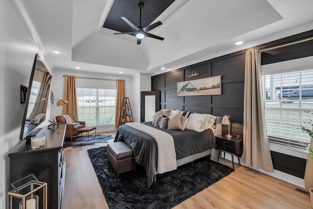 bedroom featuring ceiling fan, recessed lighting, visible vents, light wood-style floors, and a raised ceiling